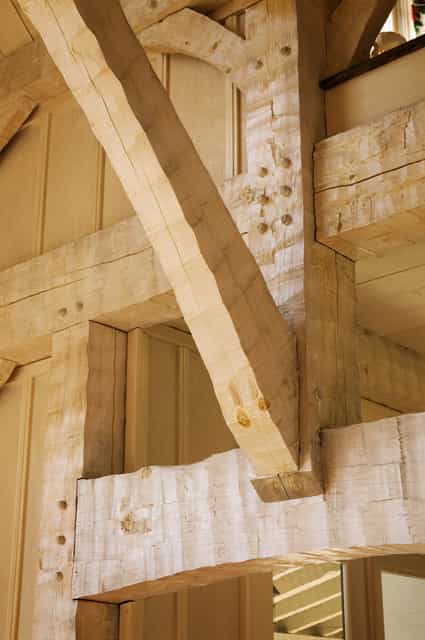 Hewn knee brace joining post and beam, pegs visible